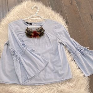 Light blue there a blouse with buttons at the back and details in the front